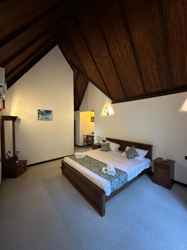 a bedroom with a large bed and a wooden ceiling at Sansun Villa in Harumalgoda West