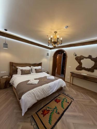 a bedroom with a large bed and a chandelier at Hotel Restorant Unaza in Voskopojë