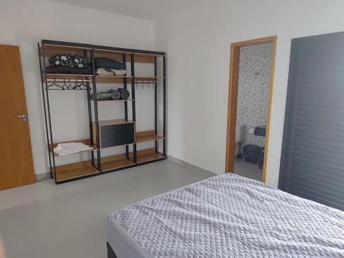 a bedroom with a bed and a shelf with clothes at Refúgio 4 Praia Indaiá Bertioga 150 mts da praia in Bertioga