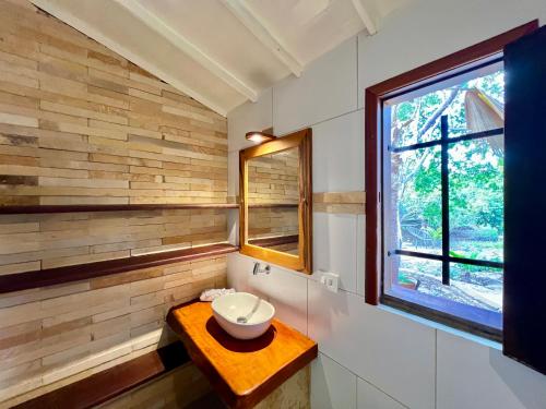 a bathroom with a bowl on a wooden table and a window at Pousada e Restaurante do Paulo in Jijoca de Jericoacoara
