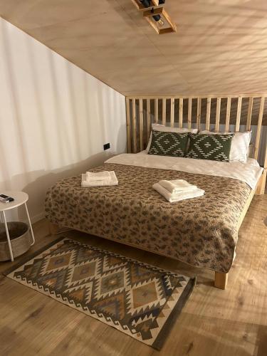 a bedroom with a bed with two pillows and a rug at Tiny Marae in Straja