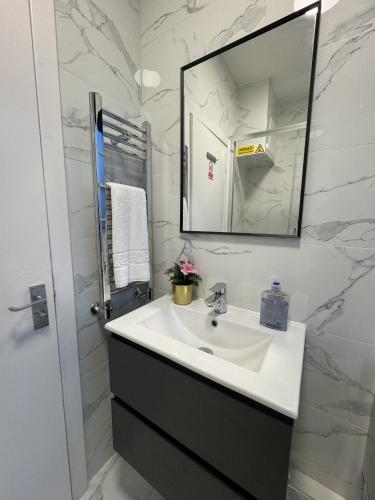 a white bathroom with a sink and a mirror at New Kings Cross Comfort in London