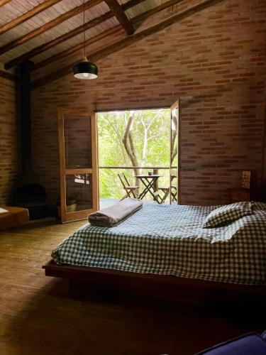 a bedroom with a bed in a room with a window at Chalé nas Árvores -Pitayas Agroturismo in Joanópolis