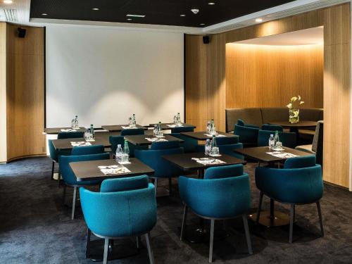 a dining room with tables and blue chairs at Mercure Paris 17 Batignolles in Paris