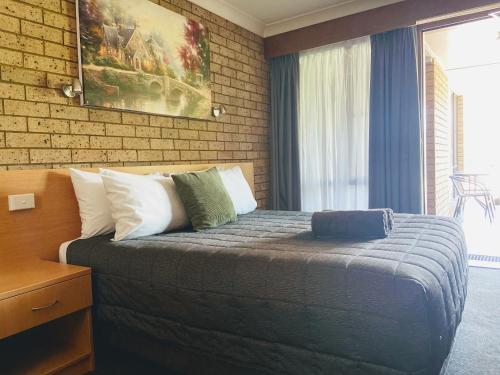 a bedroom with a bed and a brick wall at Muswellbrook Motor Inn in Muswellbrook