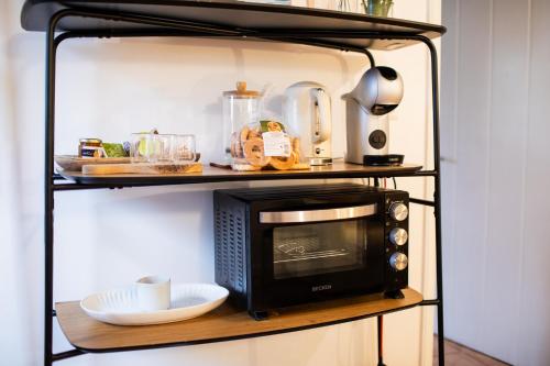a black shelf with a microwave on it at Praia - Boutique Garden Ocean View Suite in the Countryside - Vila Pilar in Ponta Delgada