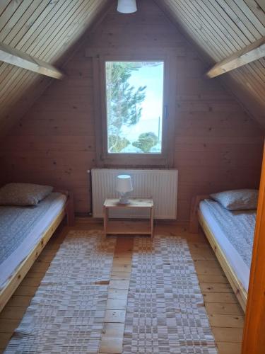 a attic room with two beds and a window at Domek za lasem in Laskowa