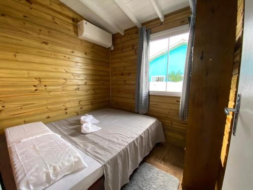 a small bedroom with a bed in a wooden room at Conforto na praia 2 Quartos com Ar Até 6 Pessoas in Imbituba