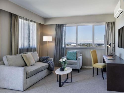 a living room with a couch and a table and chairs at The Sebel Auckland Manukau in Auckland