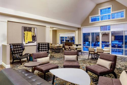 a waiting room with chairs and tables and windows at Residence Inn Worcester in Worcester