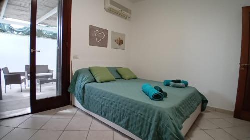 a bedroom with a bed with green sheets and a window at Solemar Salento in Marittima