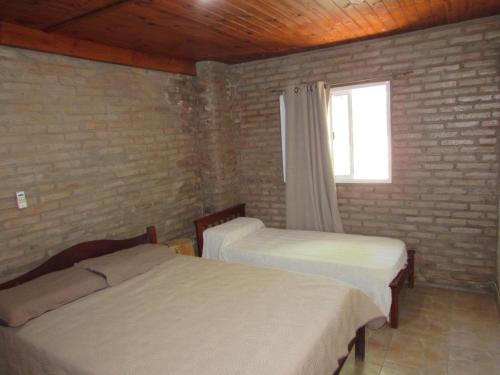 two beds in a room with a brick wall at Complejo Kallpa in Santiago del Estero