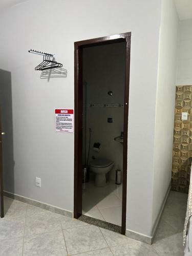 a bathroom with a toilet and a sign on the wall at Pousada Cantinho da Jú in Pirenópolis