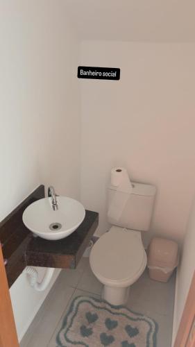 a bathroom with a white toilet and a sink at Casa 3 dormitórios 100 metros da praia in Praia Grande