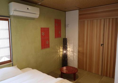 a bedroom with a bed and a door and a stool at 京都 大阪アクセス良好の和モダン民泊 静かで快適な宿泊施設です 京阪本線楠葉駅から徒歩圏内 急行特急停車駅で京都へ約30分 大阪へ約40分とアクセス良好です in Hirakata