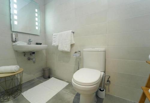a white bathroom with a toilet and a sink at Lazy Roo Hostel Saranda in Sarandë
