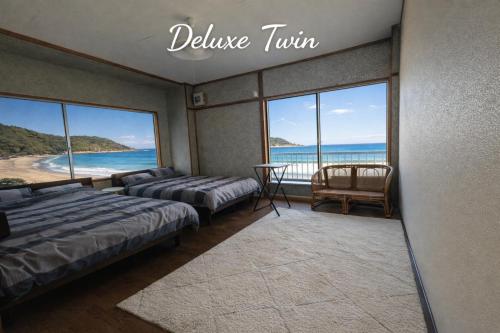 a bedroom with two beds and a view of the ocean at MACARA Guesthouse in Nichinan