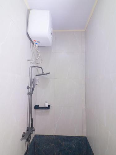 a shower in a bathroom with a white tiled wall at Pickle n Pod villa in Solo with pickle court near mall in Grogol