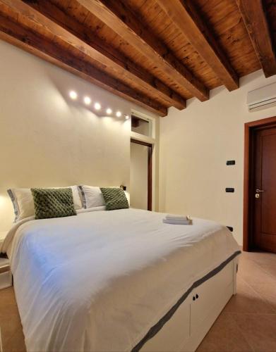 a bedroom with a large white bed with wooden ceilings at HolidHome - Soave Borgo Suite - Mini appartamento di charme nelle mura medievali in Soave