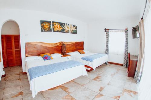 two beds in a room with white walls at Dos Mundos Pacific Resort in Monterrico