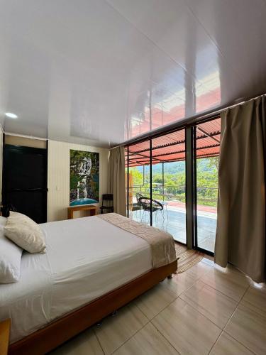 a bedroom with a bed and a large glass window at Minca Seasons Birds in Minca