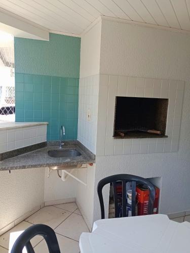 a kitchen with a sink and a tv in a room at Duplex 11 Pessoas-Churrasqueira-Próximo ao Mar in Itapema
