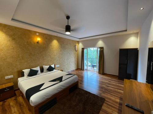 a bedroom with a bed in a room with wooden floors at Nellarachal Homestay in Ambalavayal