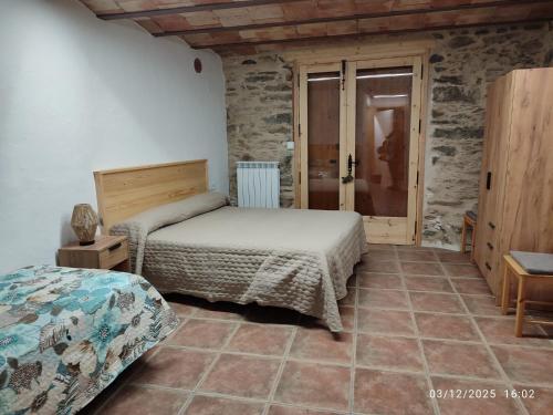 a bedroom with two beds in a room with stone walls at Cal RAFELÓ in Queralbs