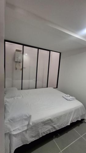 a white bed in a room with windows at Denier House Fuente de los Rosales - A 5 minutos de Centros Comerciales in Ibagué