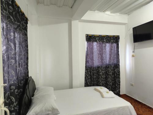 a bedroom with a bed and a black curtain at Hotel Quinchia in Quinchía