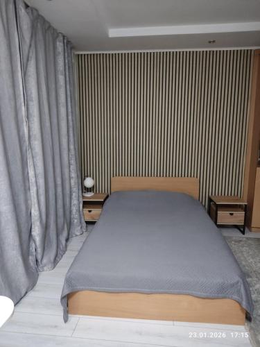 a bedroom with a bed and a striped wall at Бухар жырау 45 in Karagandy