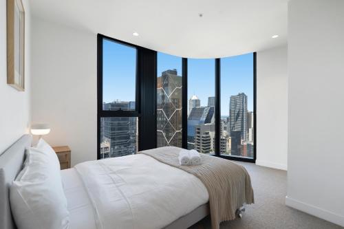 a bedroom with a white bed and large windows at Skyline City Apartment with Pool & Gym & Sauna in Melbourne