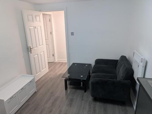 a living room with a black couch and a table at The Apartment in Oldham