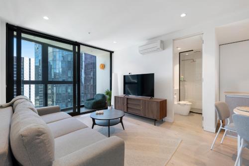 a living room with a couch and a tv at Skyline City Apartment with Pool & Gym & Sauna in Melbourne