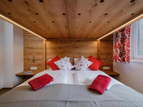 a bedroom with a large bed with red and white pillows at BergbiberLODGE L in Piesendorf