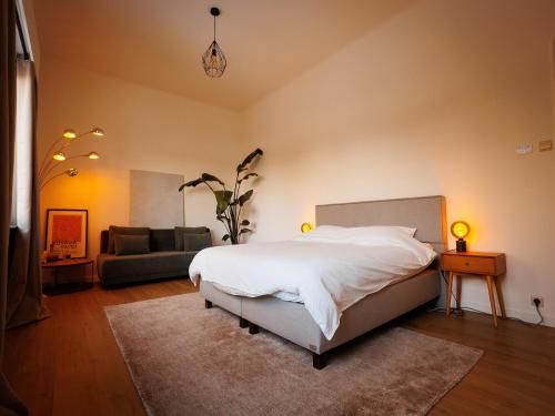 a bedroom with a white bed and a couch at LOFT-54 -Exclusive Apartment with Terrace in Zwevegem