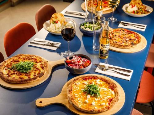 a blue table with pizzas and glasses of wine at ibis Budget Terminal 2 Manchester Airport by Accor in Hale