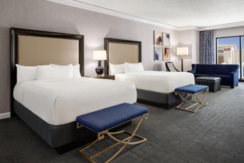 a hotel room with two beds and two chairs at Caesars Palace Hotel & Casino in Las Vegas