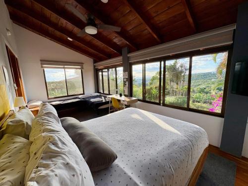 a bedroom with a large bed and large windows at Hotel Honey Bee in Alajuela