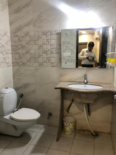 a person taking a picture of a bathroom with a toilet and sink at Hotel Confirm Inn Kota in Kota