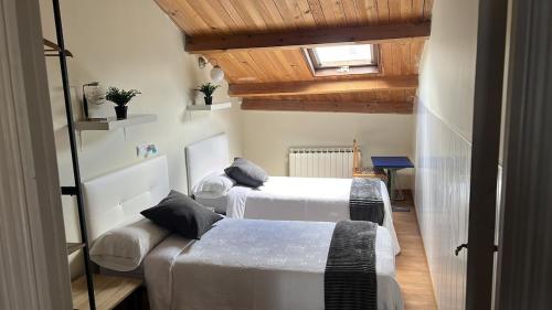 two beds in a room with wooden ceilings at Ático El Hub in León