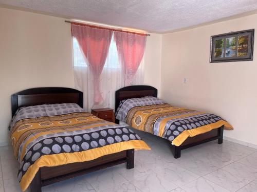 two beds sitting in a room with a window at Hostal Villa Franca in Ibarra