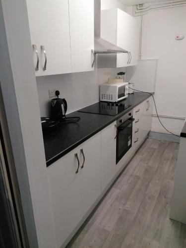 a kitchen with white cabinets and a black counter top at Regent Cosy Homes in Stoke on Trent