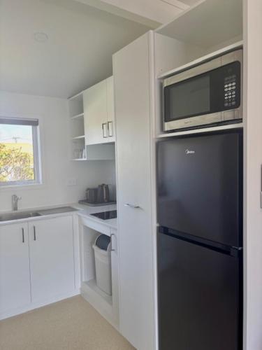 a kitchen with a black refrigerator and a microwave at Parkside Motel and Apartments in New Plymouth