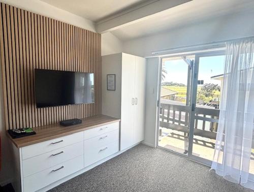 a living room with a flat screen tv and a balcony at Parkside Motel and Apartments in New Plymouth