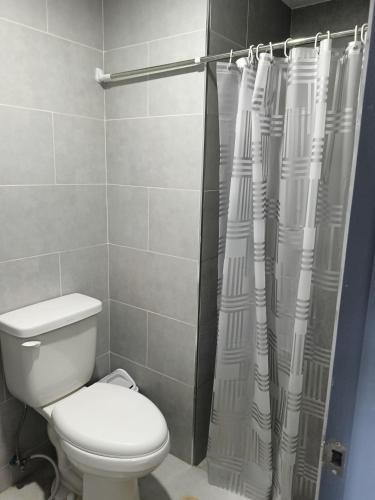a bathroom with a toilet and a shower curtain at Homey studio in jtower residences in Mandaue City