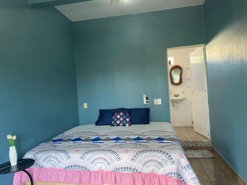 a bedroom with a bed with a blue wall at Refugio del Mar in Puerto Escondido