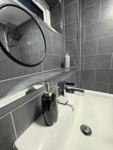 a bathroom sink with a mirror and a soap dispenser at Luxury modern guest house in Birmingham