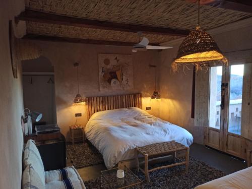 a bedroom with a bed and a chair and a lamp at Trésors des Ancêtres in Ibrahene