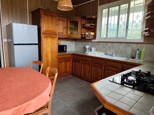 a kitchen with a table and a white refrigerator at La villa Madelon in Cilaos